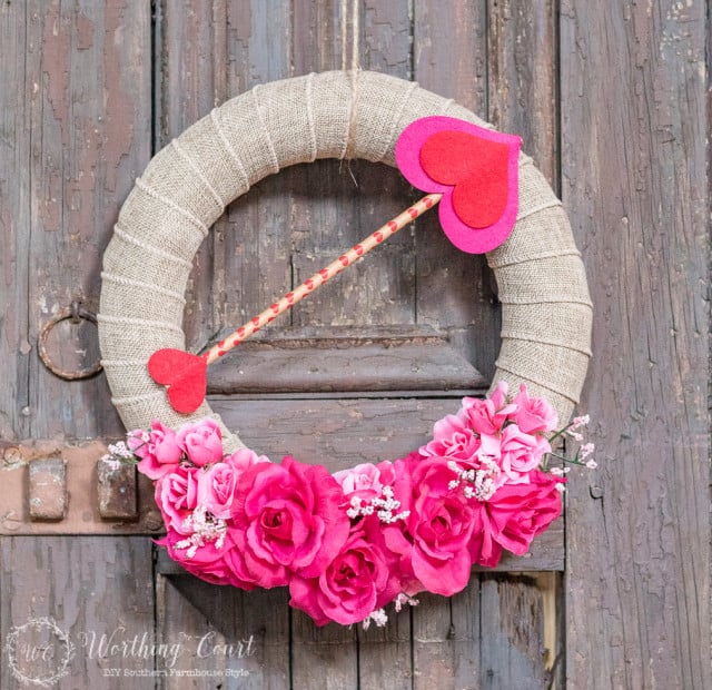 DIY Valentine's Day wreath with a heart arrow and pink flowers.