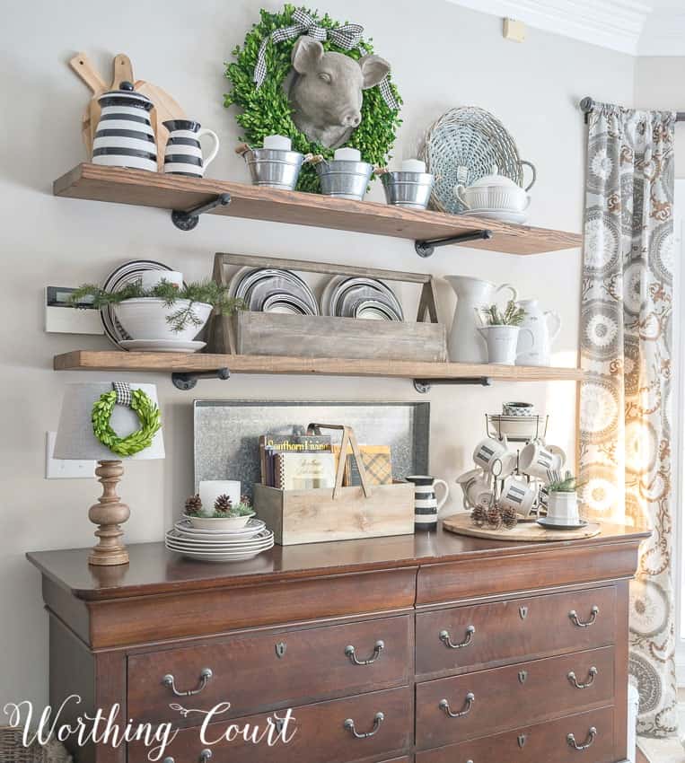 Rustic farmhouse open shelves decorated for winter with black and white dishes, wood tones, greenery and galvanized metal 