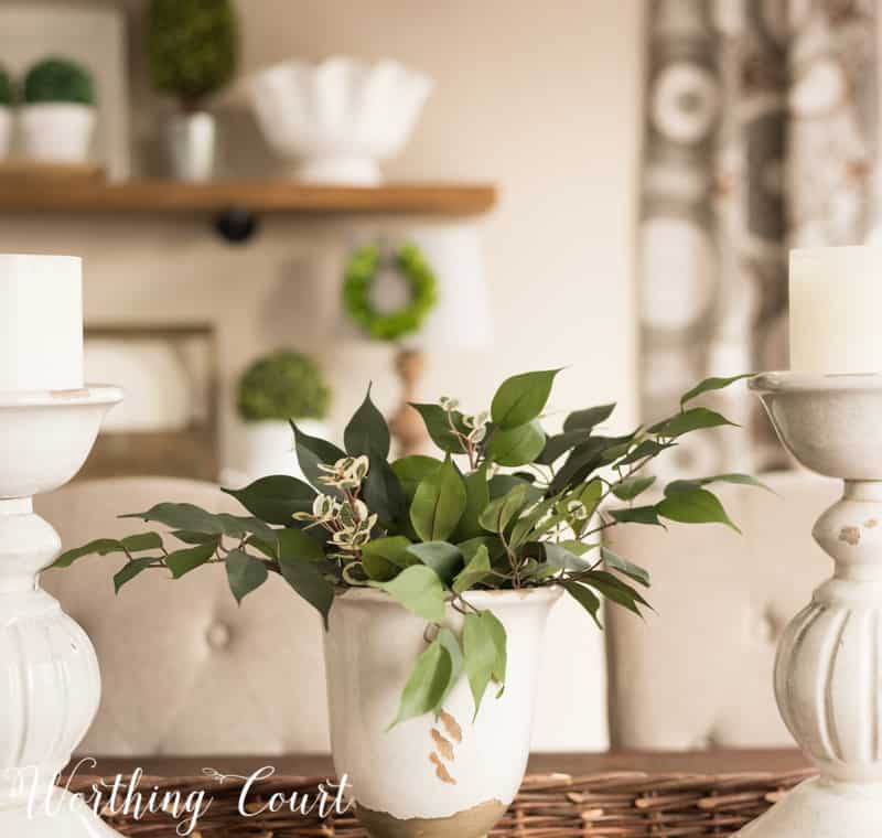 A white piece of pottery with green leaves in it.