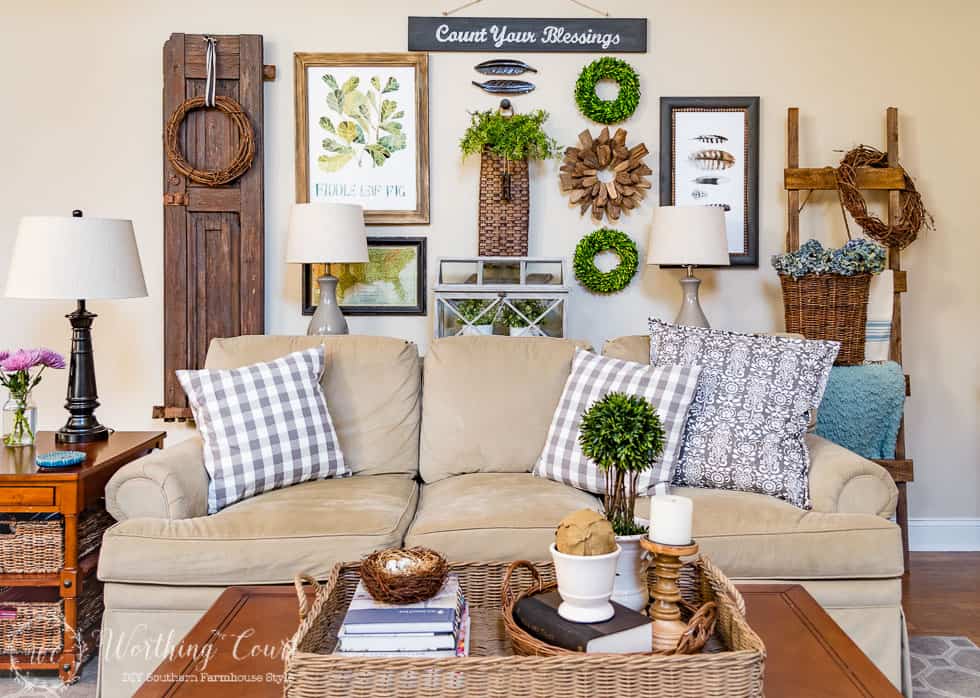 A neutral couch with throw pillows and a coffee table with a small vignette on it.