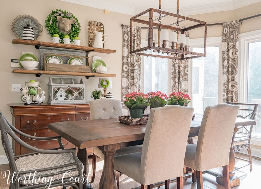 A wooden dining room table with fabric covered chairs.