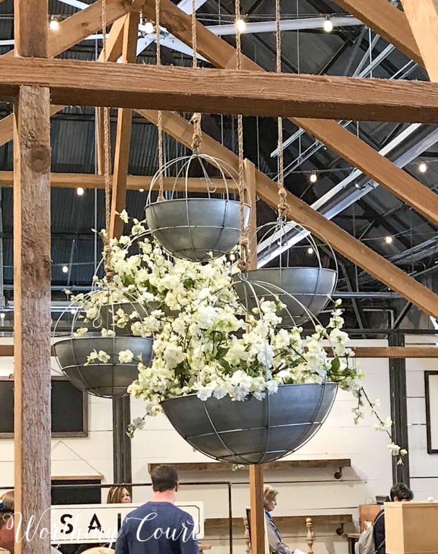 Hanging metal baskets filled with flowers at Magnolia Market #fixerupper #magnoliamarket #flowers #springdecoratingideas #summerdecoratingideas