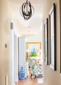 looking down a long hallway toward a living room with a colorful chair