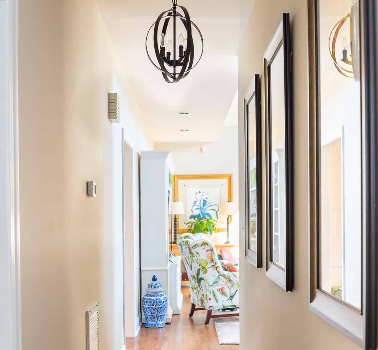 looking down a long hallway toward a living room with a colorful chair