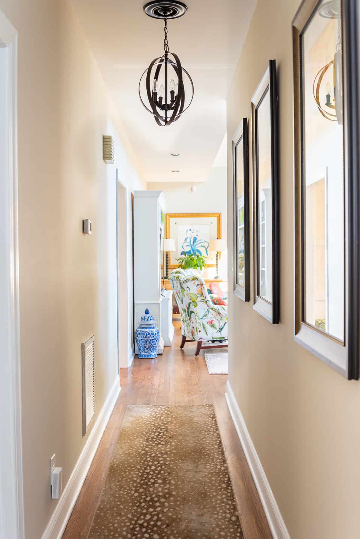 looking down a long hallway toward a living room with a colorful chair