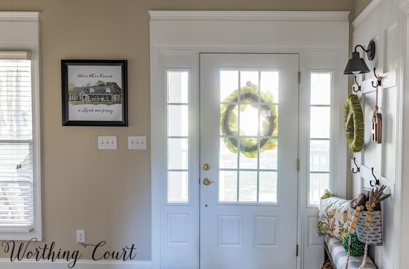 The front door with glass and a wreath hanging on the outside of the door.