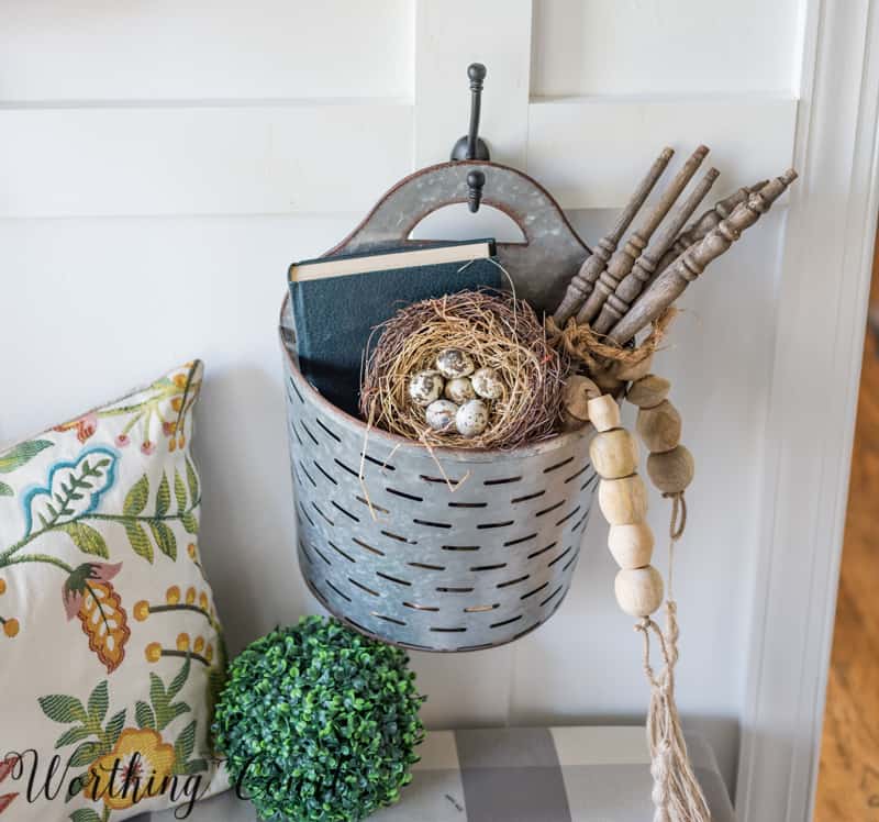 A rustic tin basket is filled with decor items.