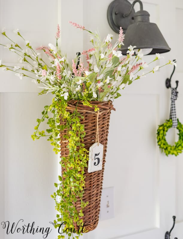 A small basket hanging on the wall is filled with flowers.