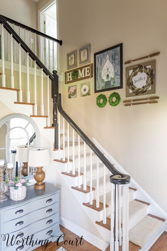 A gallery art wall is by the staircase leading up.