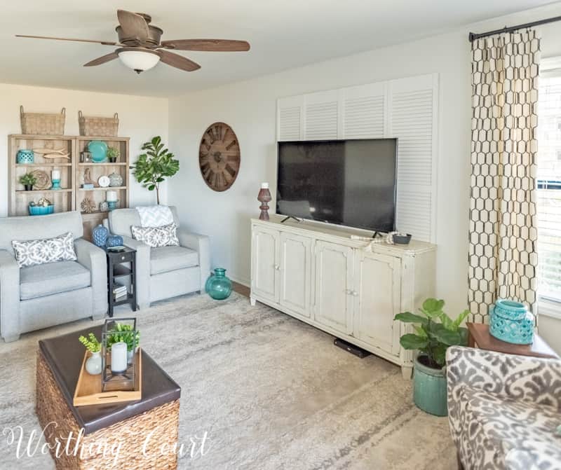 A Living Room Makeover Created With Summer In Mind - Before And After Room Reveal! Mount bi-fold doors behind a large tv to help fill the wall. #decoratearoundatv#summerdecor #summerdecoratingideas #livingroomdecor #familyroomdecor #modernfarmhousedecoratingideas #WorthingCourtBlog # #neutraldecoratingideas coastaldecoratingideas