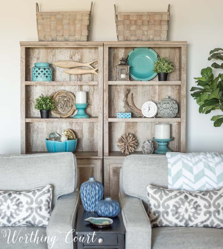 A Living Room Makeover Created With Summer In Mind - Before And After Room Reveal! Driftwood finish bookcases with coastal decor. #summerdecor #summerdecoratingideas #livingroomdecor #familyroomdecor #modernfarmhousedecoratingideas #WorthingCourtBlog # #neutraldecoratingideas coastaldecoratingideas #bookcasedecor