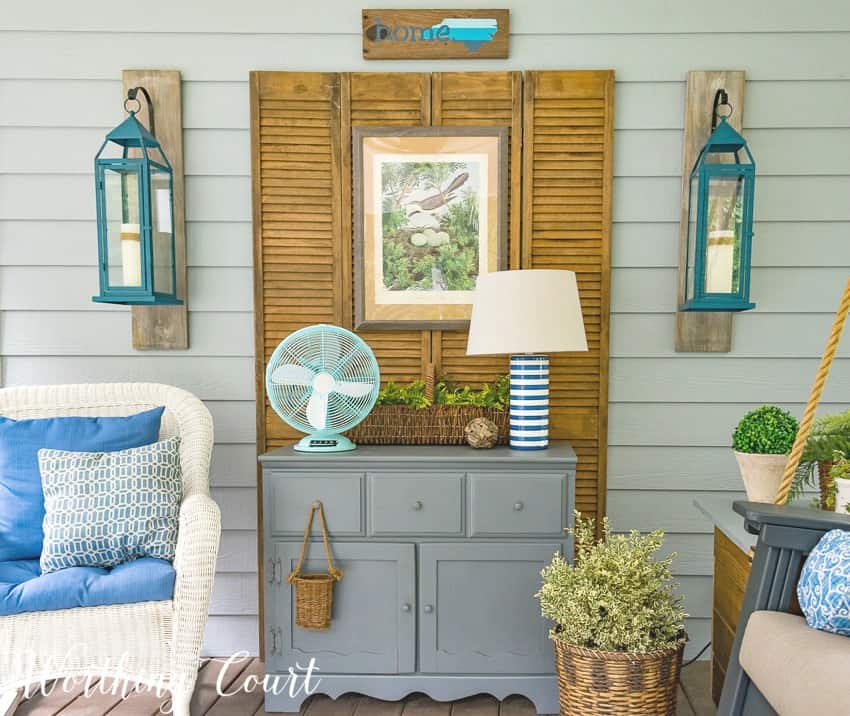 Bifold shutter doors, flanked by hanging lanterns, use as a backdrop to a vintage chest on a screen porch. #screenporch #vintagefurniture #farmhousestyle 