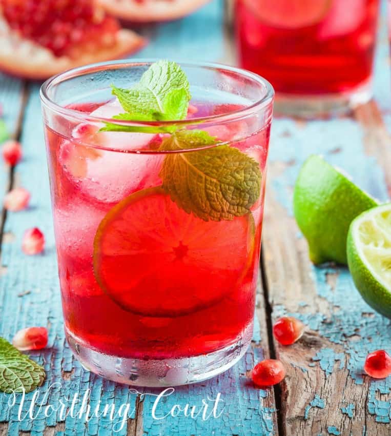 Glass filled with ice and pink lemonade on a wooden table.