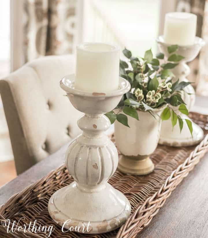 White candle sticks on a wicker tray.