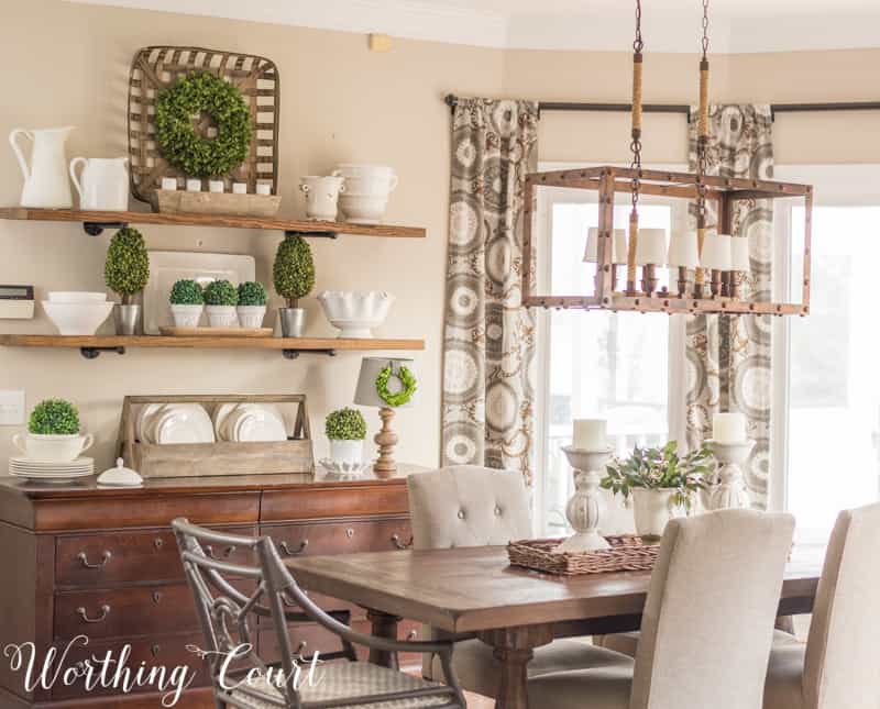 farmhouse style open shelves filled with white decor accents, dining table with white centerpiece, tobacco basket, faux greenery, industrial light fixture