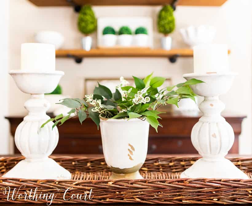 white room accessories and dining table centerpiece with white candlesticks and white vase filled with greenery in a wicker tray basket