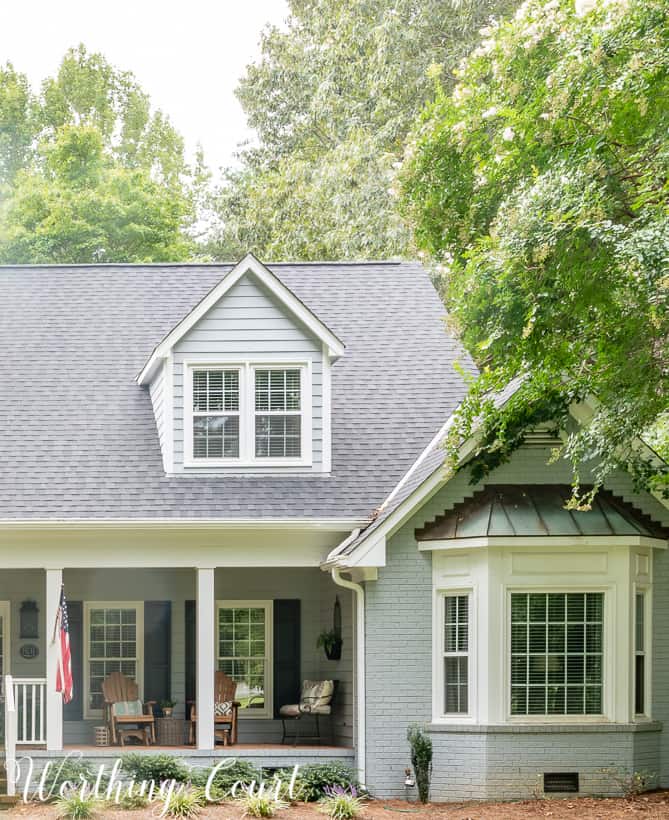 Gray painted brick house with bay window.