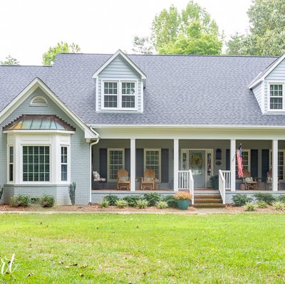 two story brick house painted gray with two bay windows and front porch