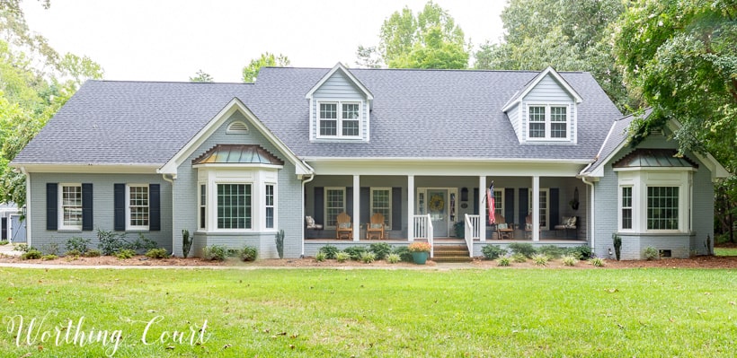 two story brick house painted gray with two bay windows and front porch