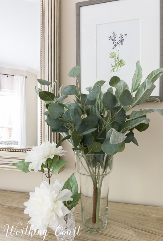 vase with faux eucalyptus stems and faux white dahlias displayed on a bedroom dresser