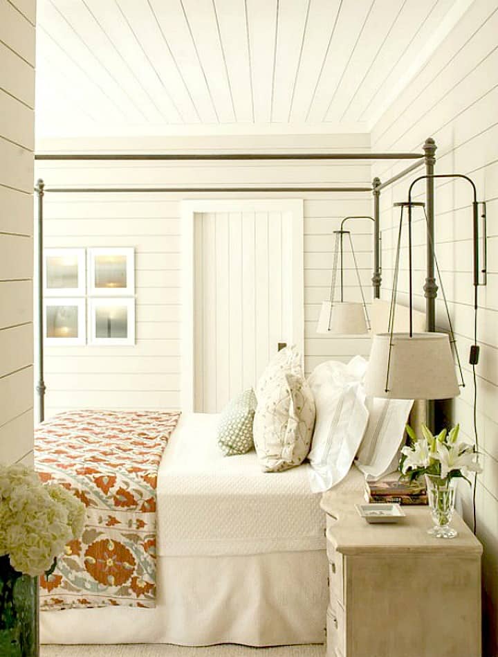 How to decorate a fixer upper farmhouse bedroom with white shiplap walls with metal bed and quilt and end table lights