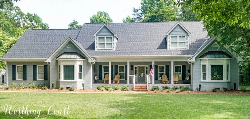 two story brick house painted gray with two bay windows and front porch