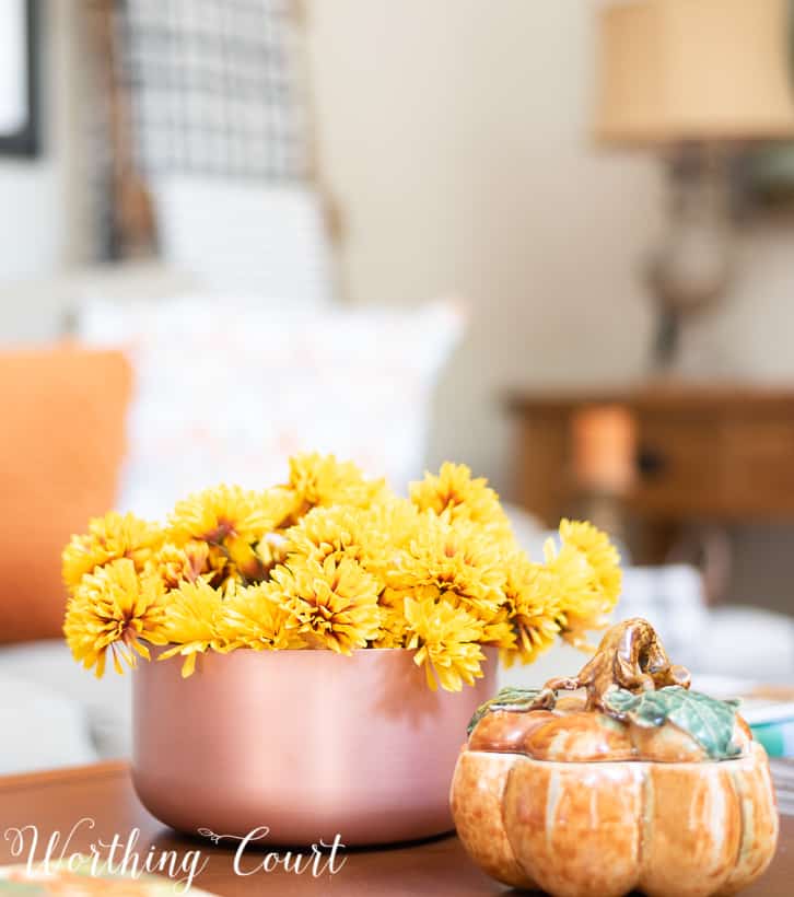 Copper bowl filled with bronze mums and pumpkin container on a coffee table