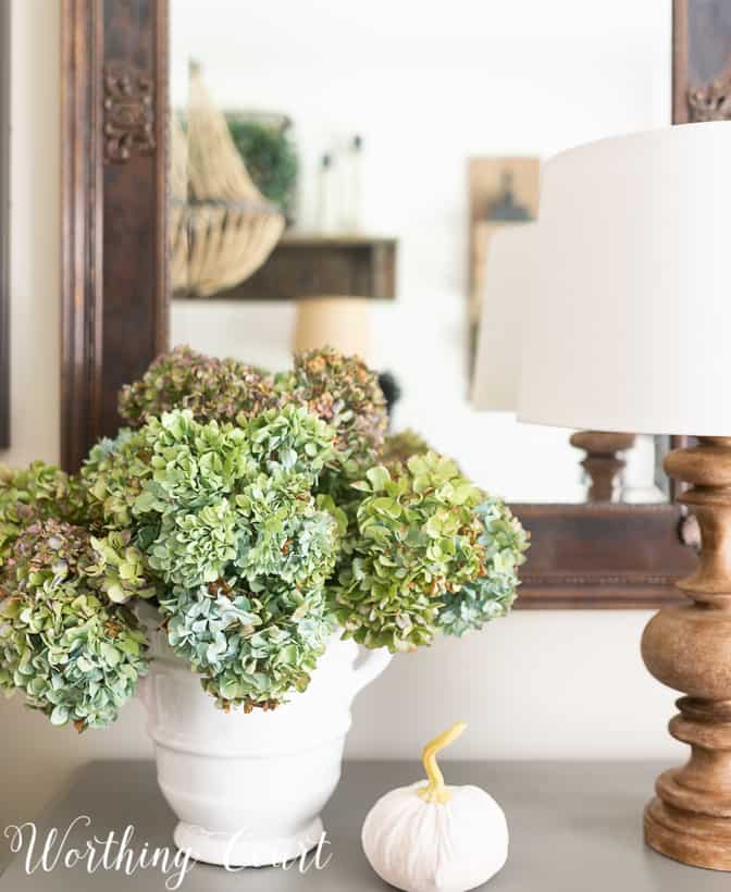 dried blue and green hydrangea arrangement in a white vase