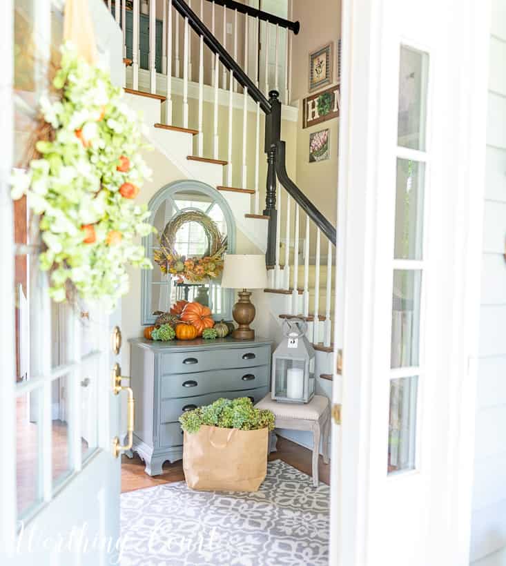 Fall foyer decorations with pumpkins on a gray chest.