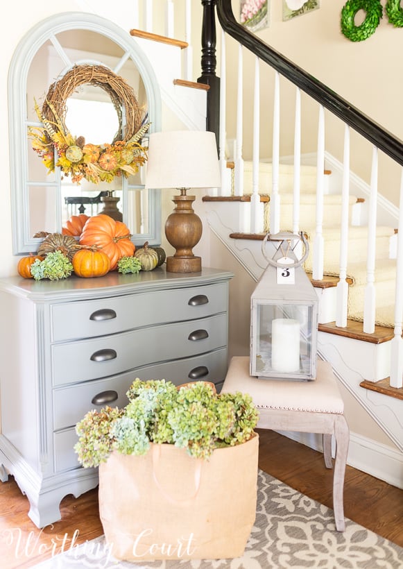 Gray chest with fall pumpkins and fall wreath.