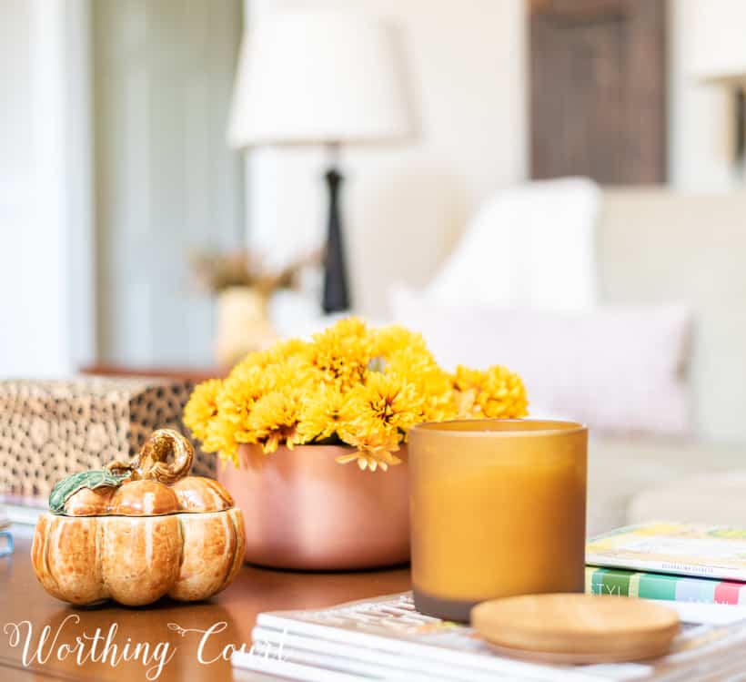 coffee table decorated for fall with mums in a copper container and a pumpkin