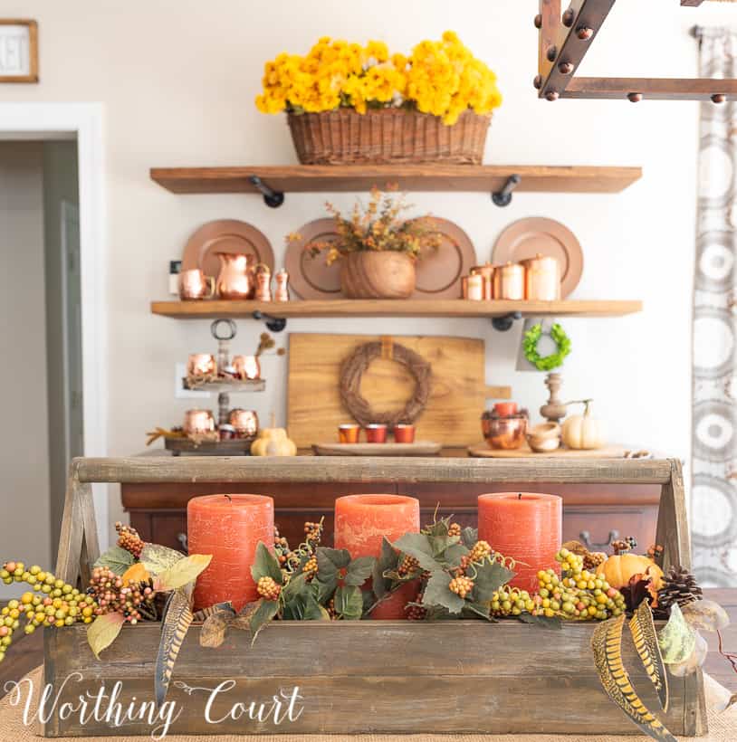 Fall centerpiece with traditional fall colors and orange candles.