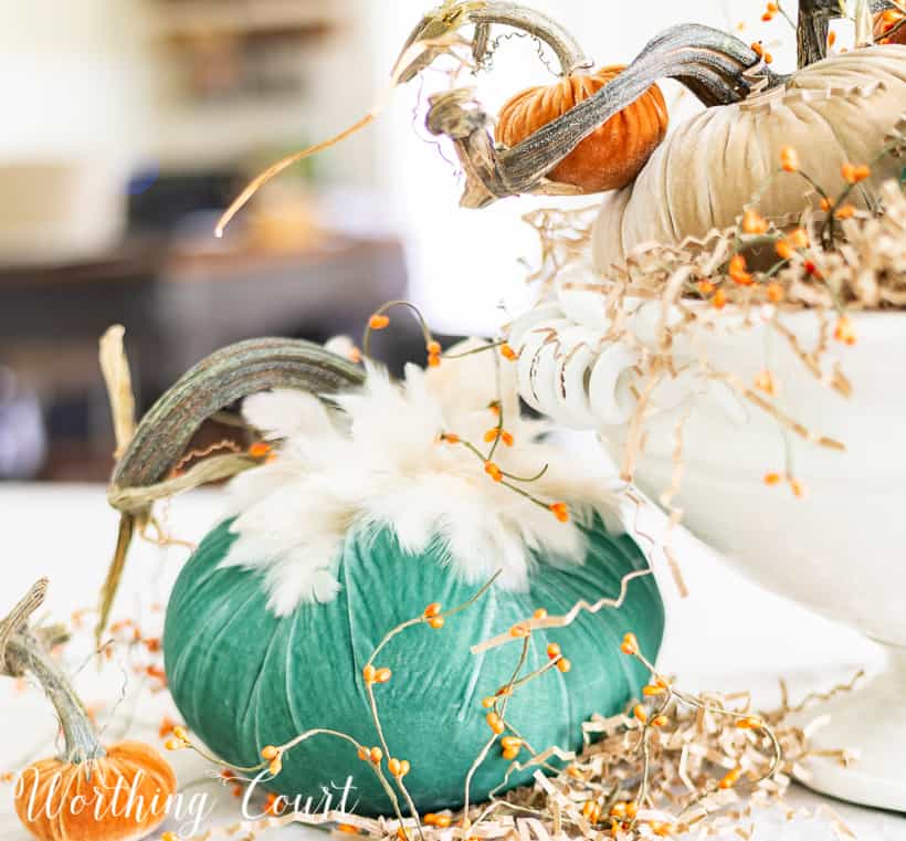 white pedestal bowl filled with various velvet pumpkins