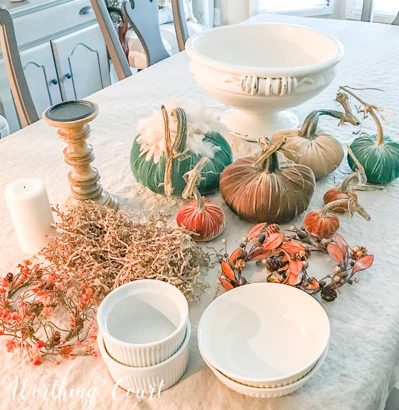 The velvet pumpkins, bowls, candlestick, with a candle and the white urn on the table.