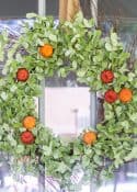 fall wreath with green leaves and faux pumpkins