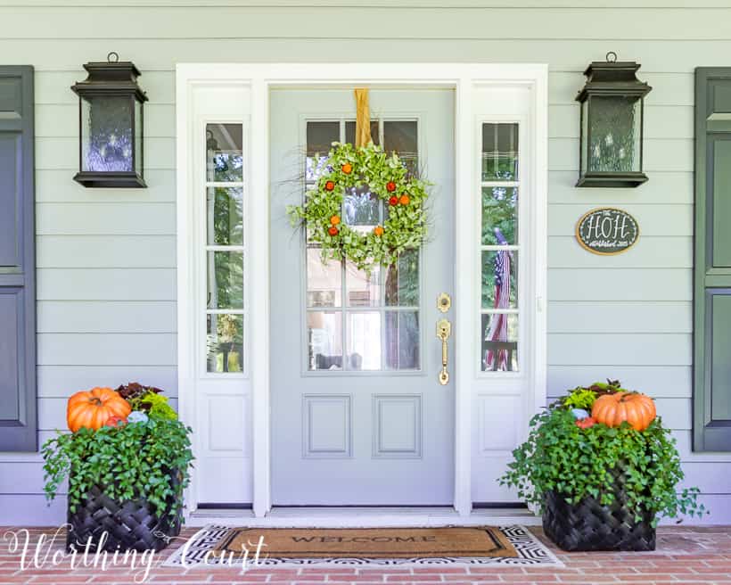 The front porch flanked by two planters with pumpkins and a wreath on the door.