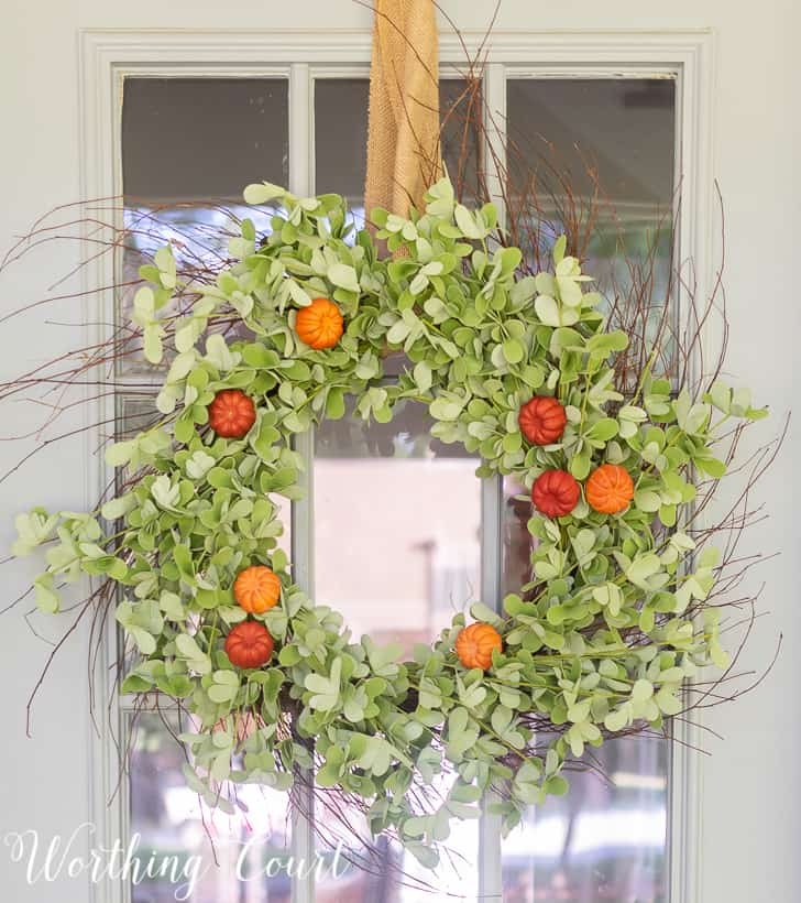 Up close picture of the green wreath with mini pumpkins on the door.