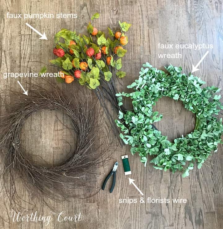 fall wreath with faux pumpkins and green leaves