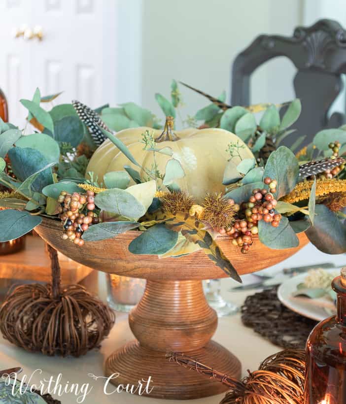 faux pumpkin with eucalyptus leaves displayed on a pedestal
