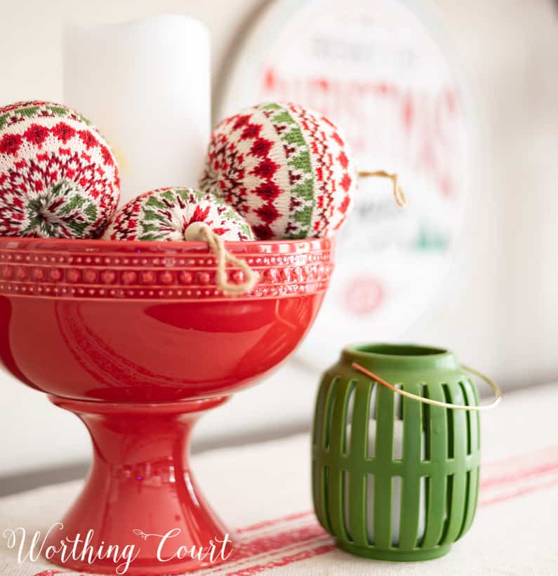 A red pedestal bowl filled with fabric ornaments.