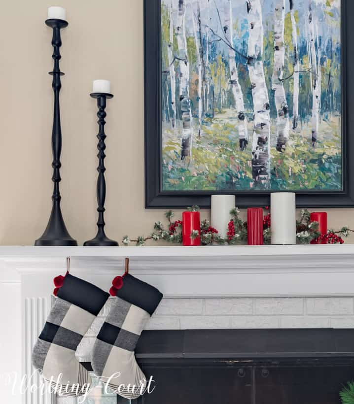 There are tall black candlestick holders on the mantel.