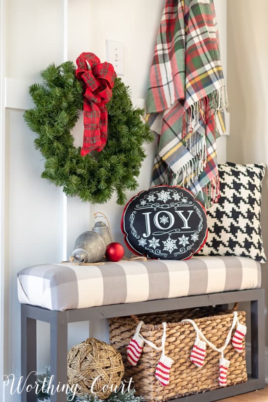 Christmas decorations on a bench with a JOY pillow.