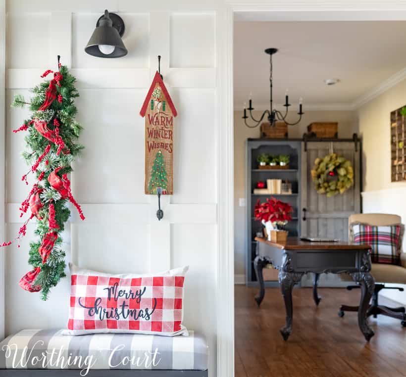 Christmas foyer decor with a plaid pillow on the bench that says Merry Christmas.