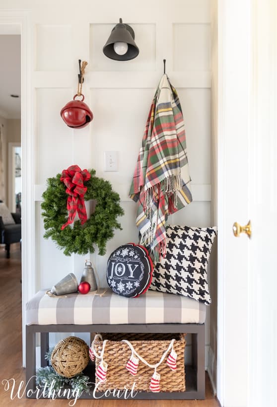 A throw blanket is hanging beside a wreath on the wall.