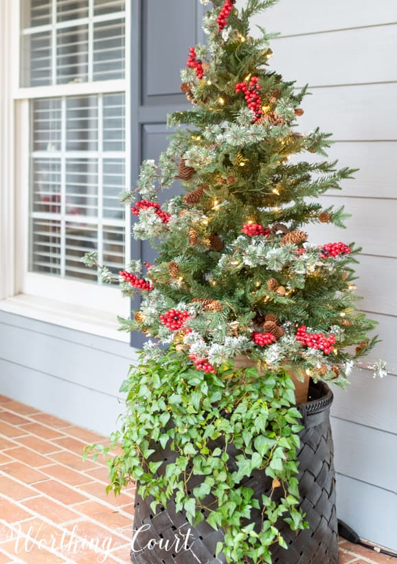 Up close picture of the basket at the front door with a Christmas tree in it.