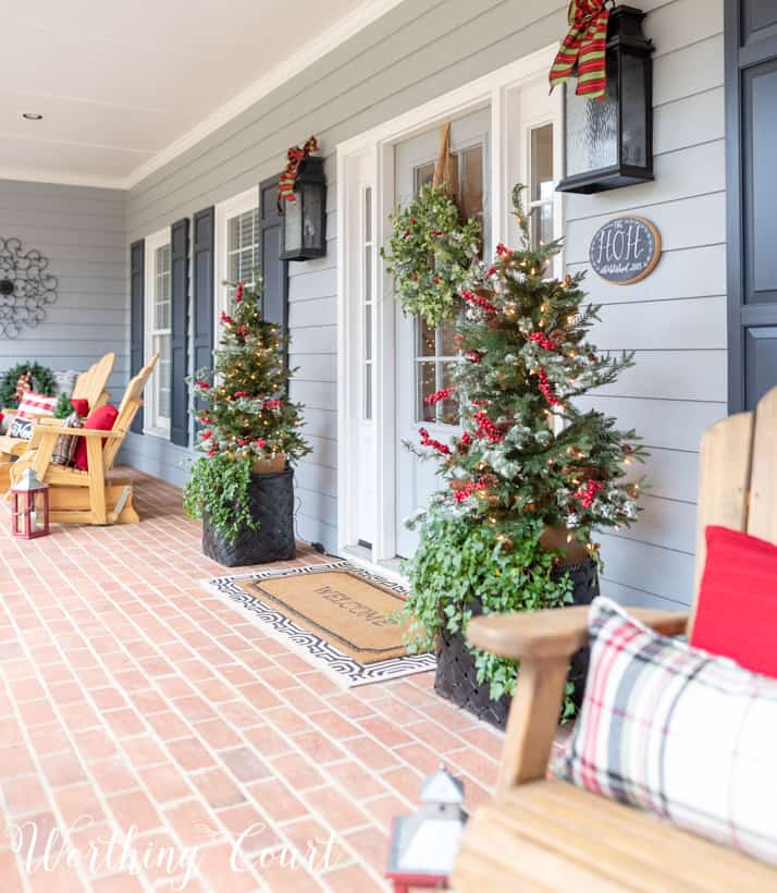 Christmas front porch with Adirondack chairs that have plaid and red pillows on them.