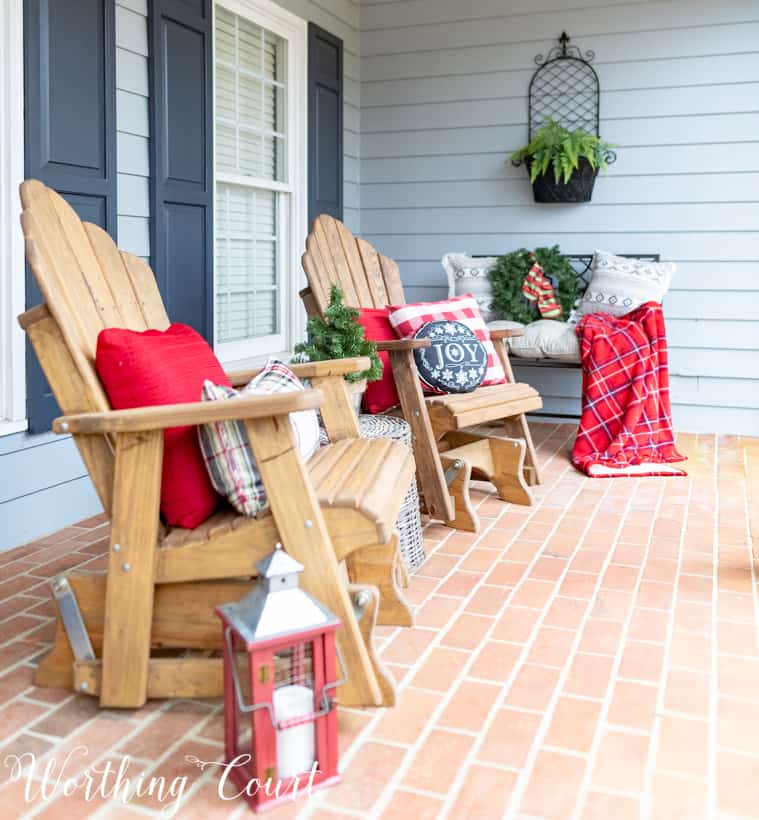 Adirondack chairs with red and plaid cushions and throw blankets are on the chairs.