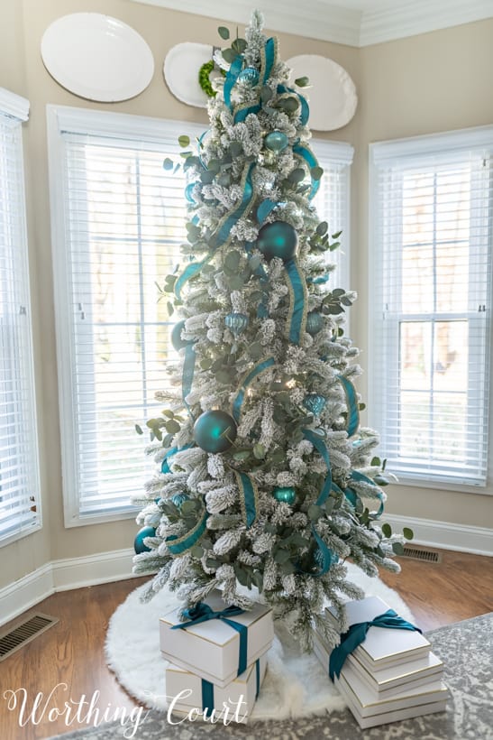 Flocked Christmas tree with teal decorations.