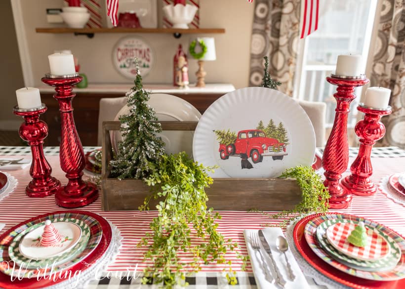 Christmas table centerpiece with a wooden toolbox filled with mini trees and plates with red trucks.