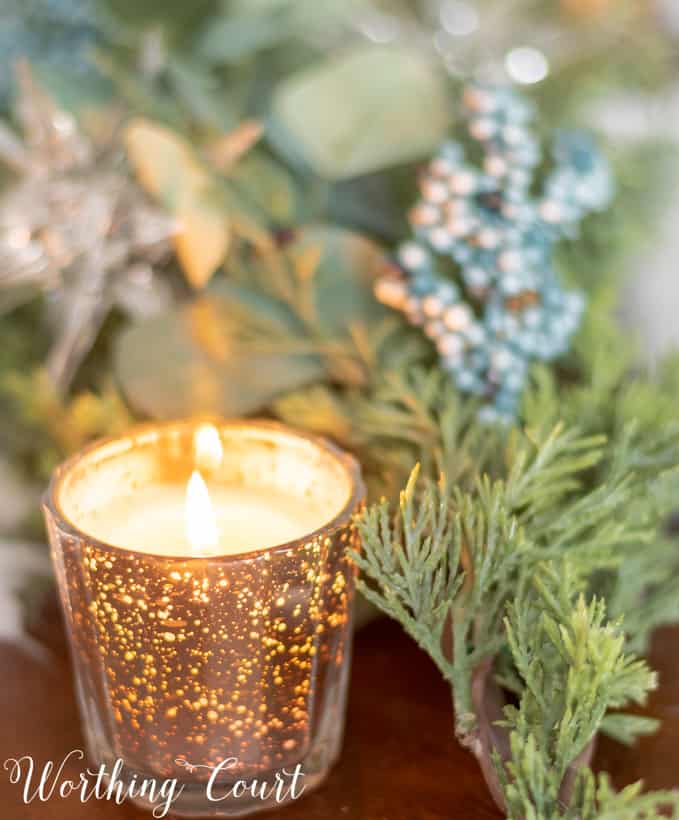 Mercury glass candle votive on the table and is lit.